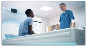 Doctor standing over a male patient about to have an MRI for mens health